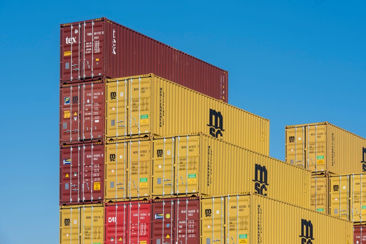 Mastering the First Impression: Your intriguing post title goes here Colorful shipping containers stacked high under a clear blue sky, displaying industrial logistics.