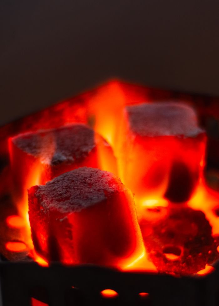 Intense close-up of red-hot charcoal briquettes, glowing with heat and ready for grilling.