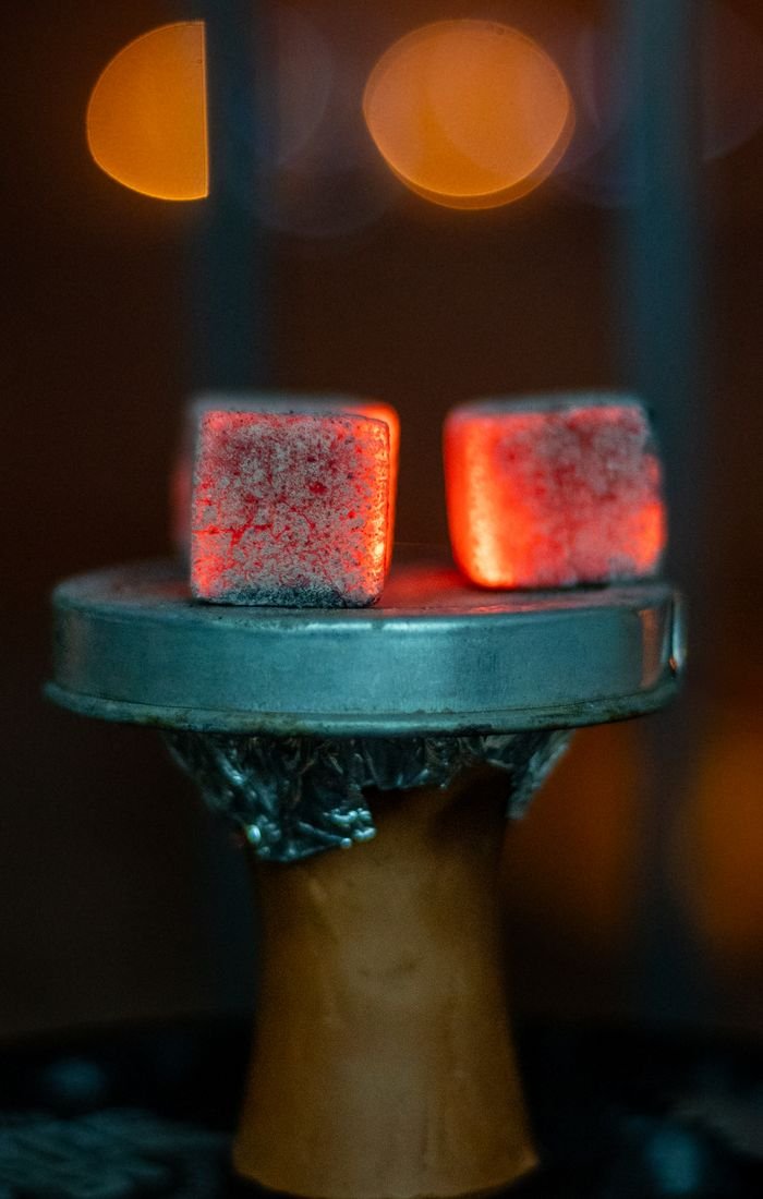 A close-up image of glowing coals on a hookah, showcasing vibrant bokeh background.